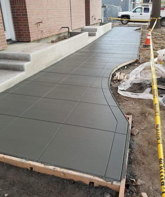 A dark stamped decorative concrete walkway curving alongside a brick building